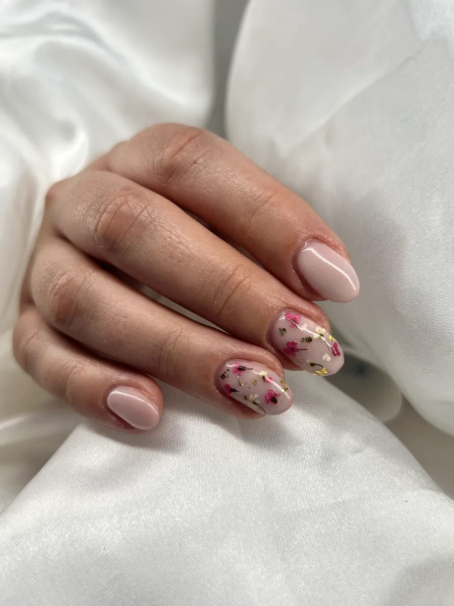 Manicura nude con flores secas prensadas dentro del esmalte.